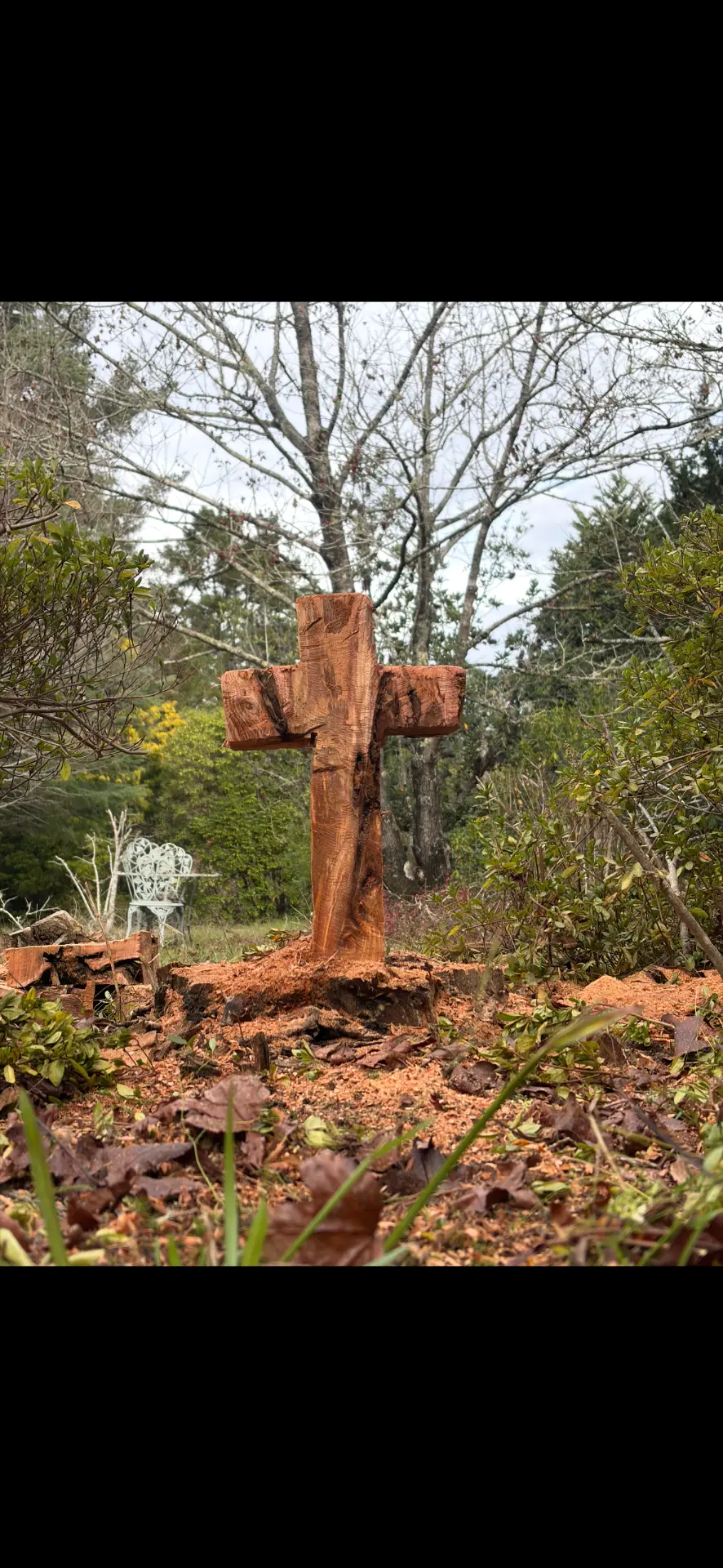 Timber cross carved from a tree stump in a country garden