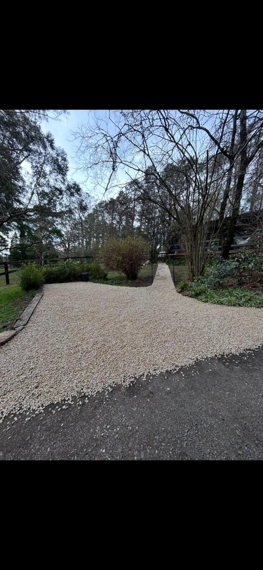 Wide gravel entry driveway laid at a rural property under gum trees