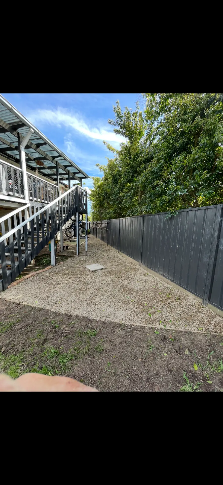 New gravel side path laid along a dark fence beside a timber staircase